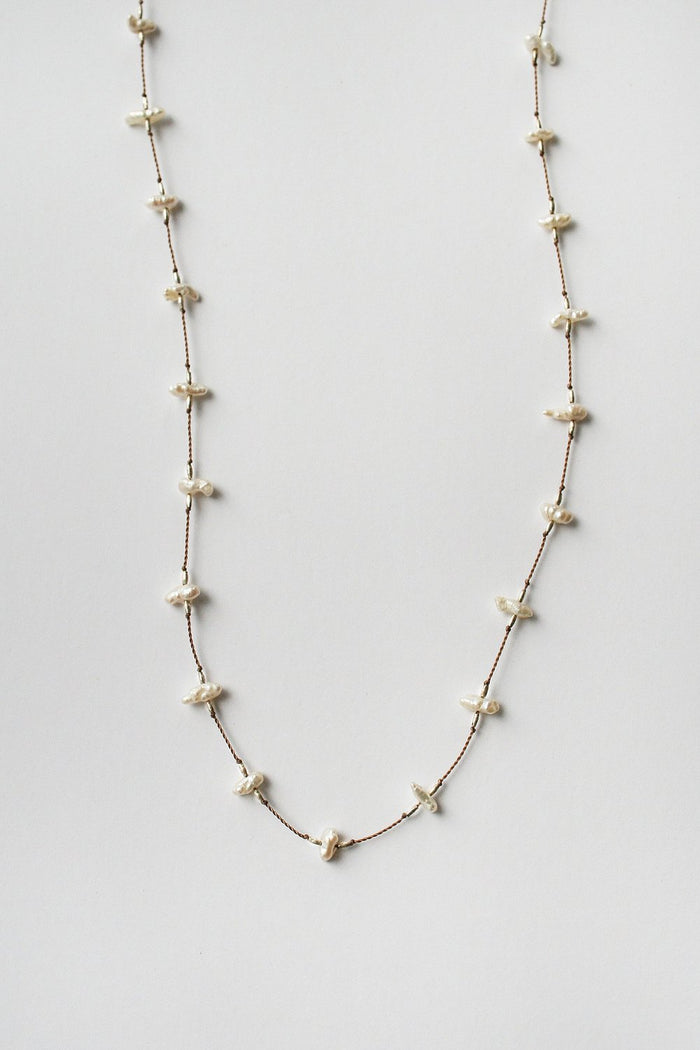 Long keshi pearl necklace, close-up of white drop pearls and gold-tone links