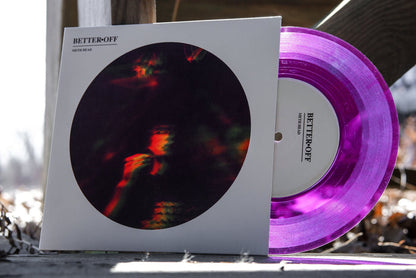 The vinyl now appears bright purple in the light with the words "better off" on it peek out of a white cover with a blurry rainbow image of a man. The words "Better Off" and "Meth Head" are at the top of the cover. The vinyl rests against wooden stairs that are outside.