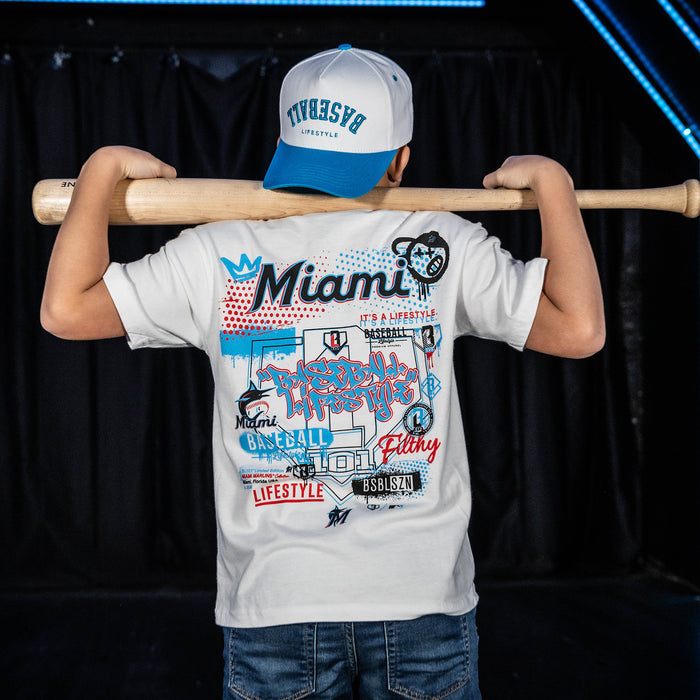 Youth model wearing white youth graphic tee with "Miami Marlins Drip" design