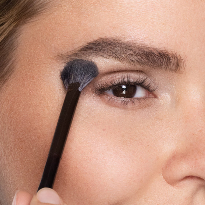 Close-up of a person applying makeup with a brush to their eye.