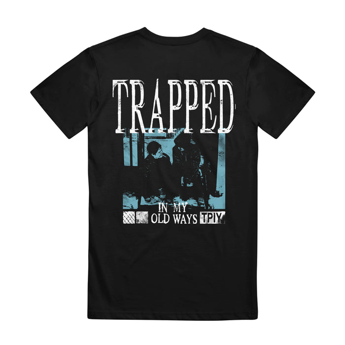 This black The Plot In You graphic tee shows two seated figures behind a fence, bold “TRAPPED” text, and “IN MY OLD WAYS TPIY” below—all styled with a distressed blue tint for standout My Old Ways vibe.