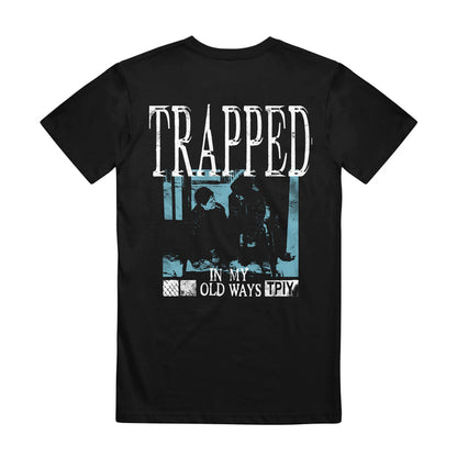 This black The Plot In You graphic tee shows two seated figures behind a fence, bold “TRAPPED” text, and “IN MY OLD WAYS TPIY” below—all styled with a distressed blue tint for standout My Old Ways vibe.