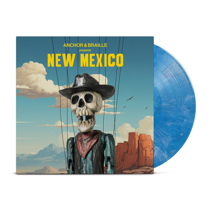 An opaque blue vinyl peeks out of a mainly blue jacket with an image of the desert with a blue sky with clouds. In front of the background is a skeleton dressed as a western cowboy with strings holding him up. The yellow text on the jacket reads "Anchor&Braille presents New Mexico".