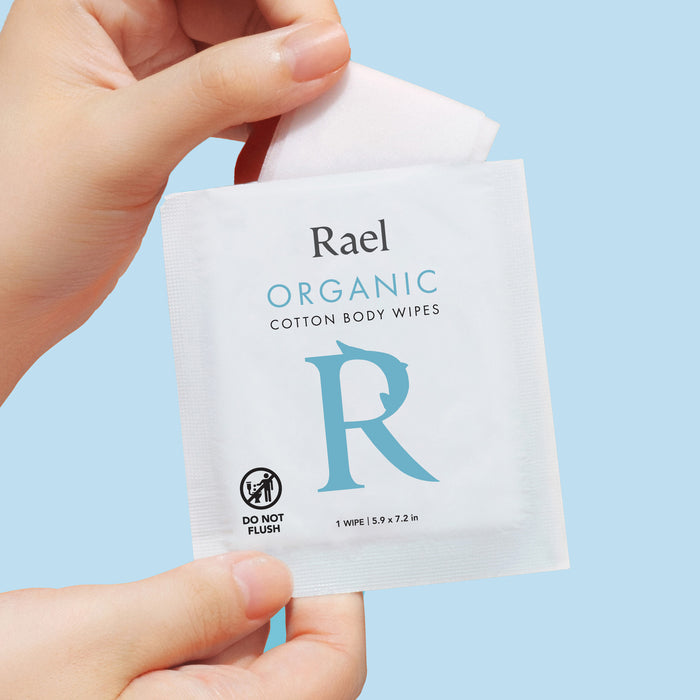 Model pulling a wipe from an individually wrapped package of Rael Organic Cotton Body Wipes.