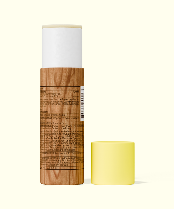 Sun Bum Paper Tube SPF 50 Sunscreen Face Stick showing back label and yellow cap removed on pale background.