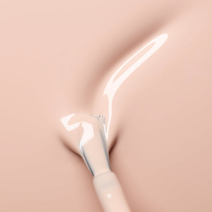 A close-up of a brush applying Manucurist's Pastel Pink nail polish, a creamy shade with subtle beige undertones, onto a smooth surface, creating a glossy, curved stroke.