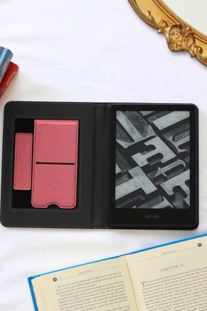 Black leather-bound kindle with pink and textured interior on a white surface.