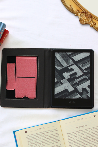 Black leather-bound kindle with pink and textured interior on a white surface.