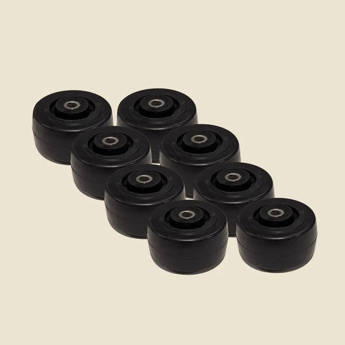 Set of eight black Pilates reformer guide wheels with steel bearings on beige background.