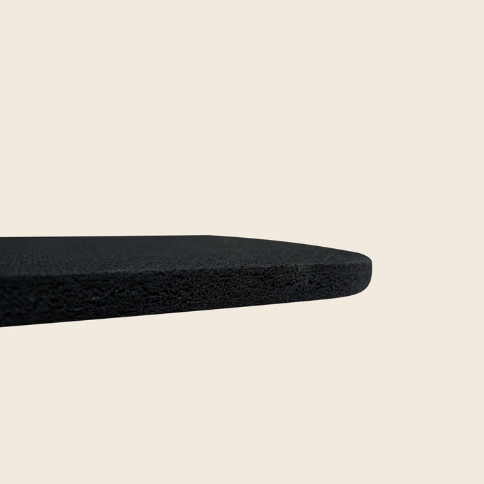 Corner of a thick black Gratz Pilates rubber pad showing its dense textured edge.