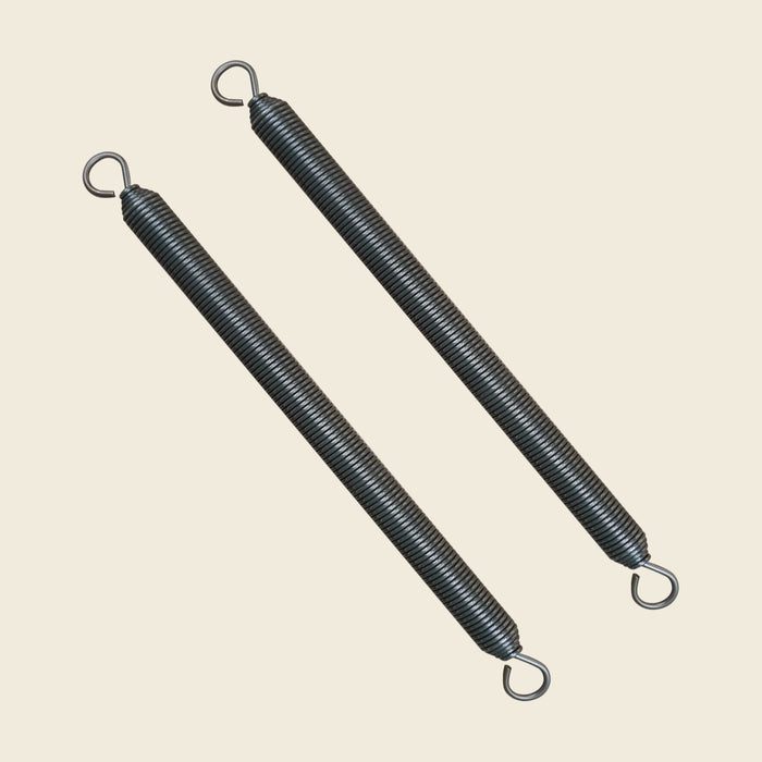 Pair of coiled steel Wunda Chair springs with looped hooked ends on beige.
