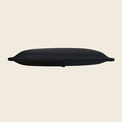 Black upholstered Pilates pillow for Reformer shoulder blocks, shown from a low side angle.