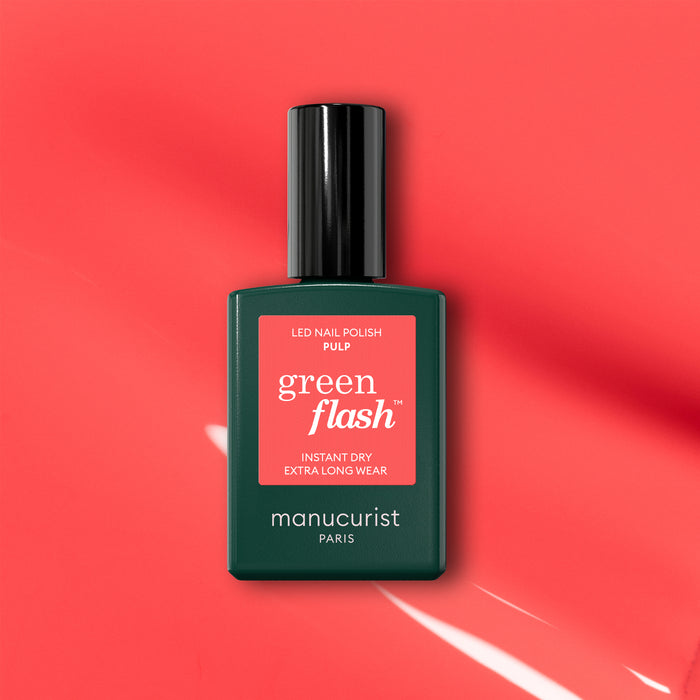 A bottle of Manucurist Pulp gel polish is displayed on a coral pink background with light reflections. The label reads "Pulp, Instant Dry, Extra Long Wear.