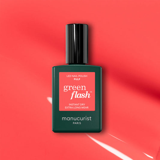 A bottle of Manucurist Pulp gel polish is displayed on a coral pink background with light reflections. The label reads "Pulp, Instant Dry, Extra Long Wear.