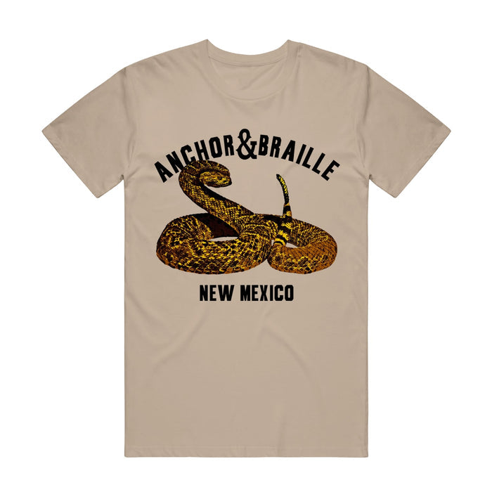 A tan shirt has an image of a rattlesnake with the words "Anchor&Braille; New Mexico".