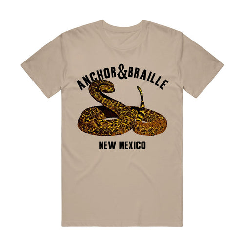 A tan shirt has an image of a rattlesnake with the words "Anchor&Braille; New Mexico".