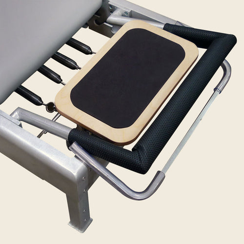 Wooden reformer standing platform with black non-slip pad mounted on a Pilates reformer frame.