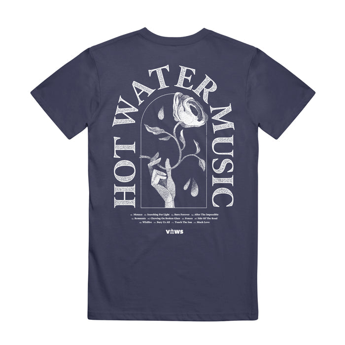 Hot Water Music navy Comfort Colors tee with bold white “HOT WATER MUSIC” text circling a white rose graphic. Tour dates/locations are in small text below, finished with the VLVVS logo.