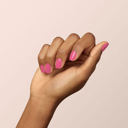 A hand with medium brown skin appears against a plain light background. The nails are neatly manicured and painted with Manucurist's Rose polish, giving them a glossy, vibrant pink finish.