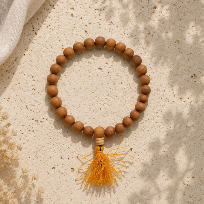 Wooden beaded bracelet with a yellow tassel on a textured beige surface