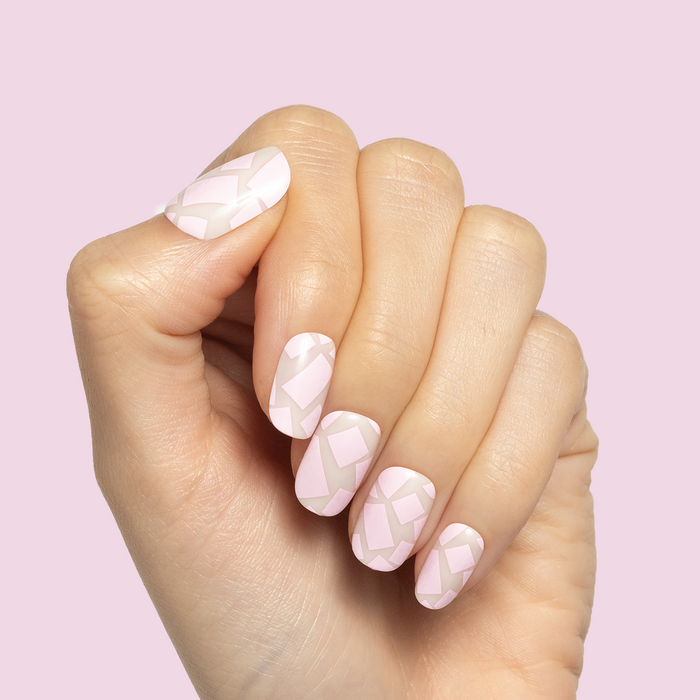 Scattered Squares | Short | Squoval - Tab Press-On light pink press-on nails with abstract square pattern on hand against pink background