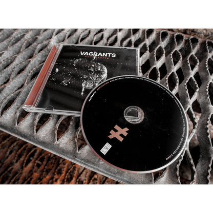 Square CD with VAGRANTS written in white font. Below that there is smaller font that says SEPARATION. The album art is a black and white image of a light bulb shattering. Laying on top of the cover is a black disc with a not equal to sign in the bottom. Both are laying on top of stairs.