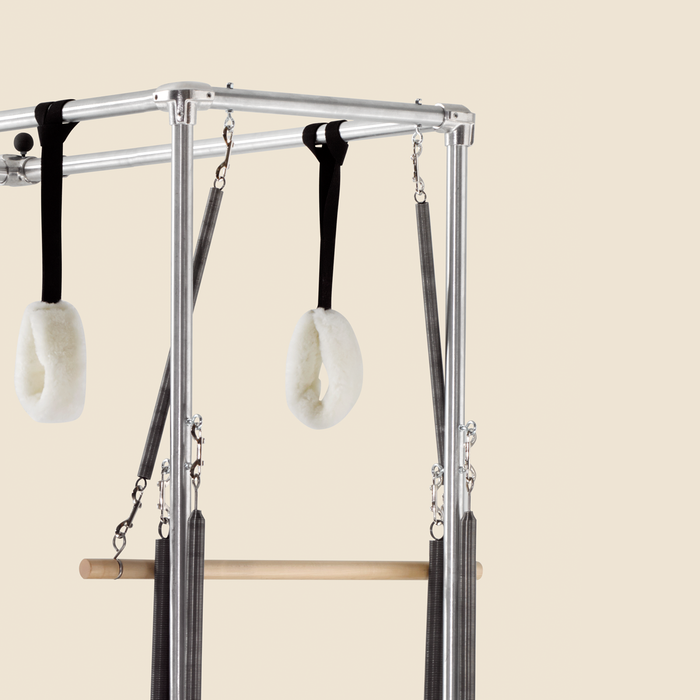 Pair of sheepskin loop canvas straps hanging from a Gratz Pilates Cadillac frame.