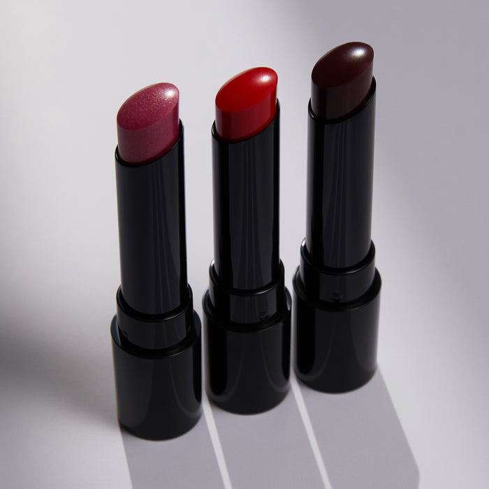 Three black lipsticks with different colored caps on a light gray background