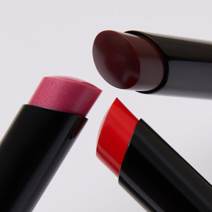 Three lipsticks in red, pink, and brown on a light gray background