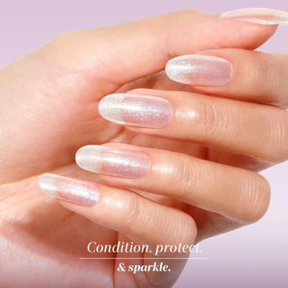 A hand with long, natural nails painted in LONDONTOWN Shimmering Nail Highlighter - Mirror Ball against a soft pink background. Text reads: "Condition, protect, & sparkle.