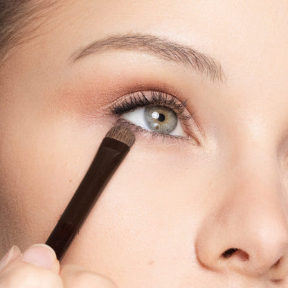 Close-up of a person applying eyeliner with a brush.