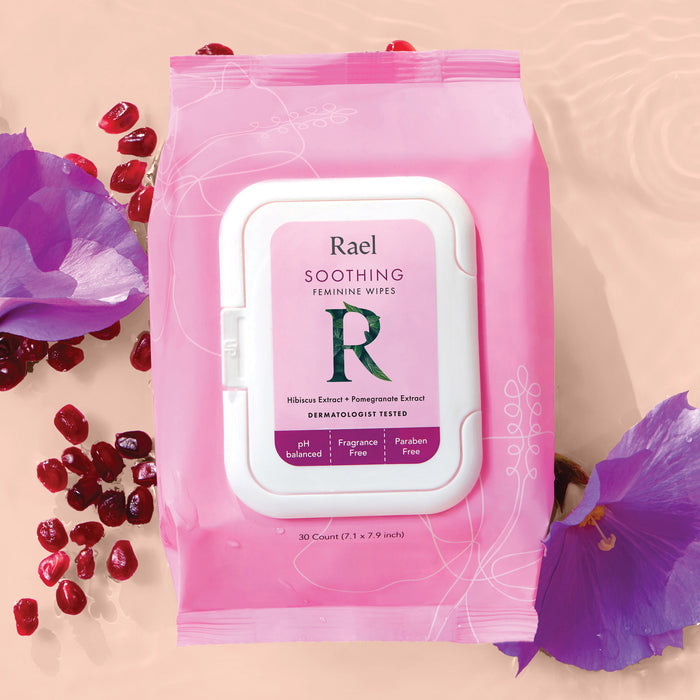 Package of Rael Soothing Feminine Wipes on a water background with purple flowers and pomegranate seeds.