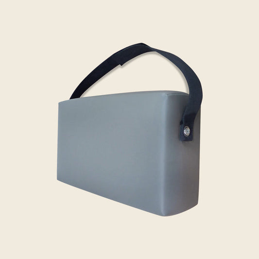 Grey upholstered Gratz Pilates spacer box with a black carrying strap handle.