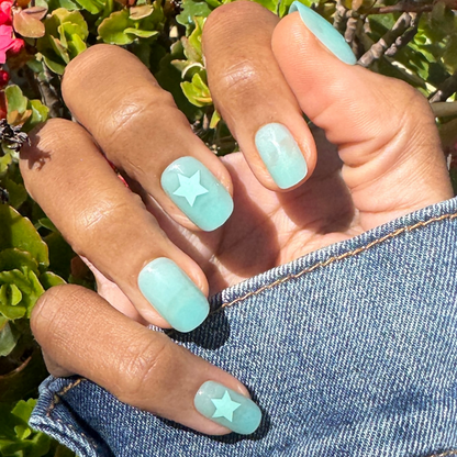 Spring Stars | Short | Squoval - Tab Press-On nails in pastel mint with star accents on hand outdoors by green foliage
