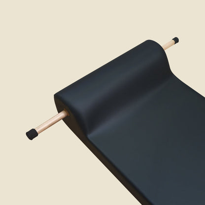 Wooden insert handles with black rubber tips fitted into a rolled black Pilates mat.