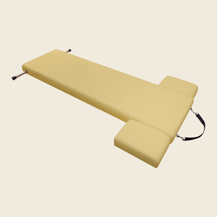 Beige Pilates mat with metal insert handles at one end and a black carry strap.