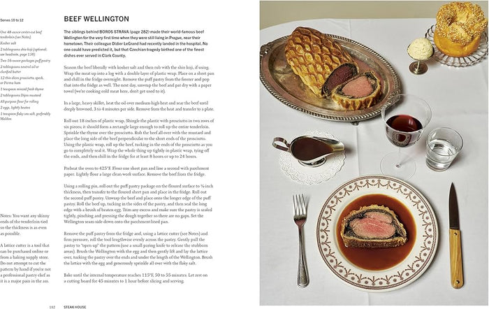 Open cookbook spread with Beef Wellington on a platter and cups and cutlery