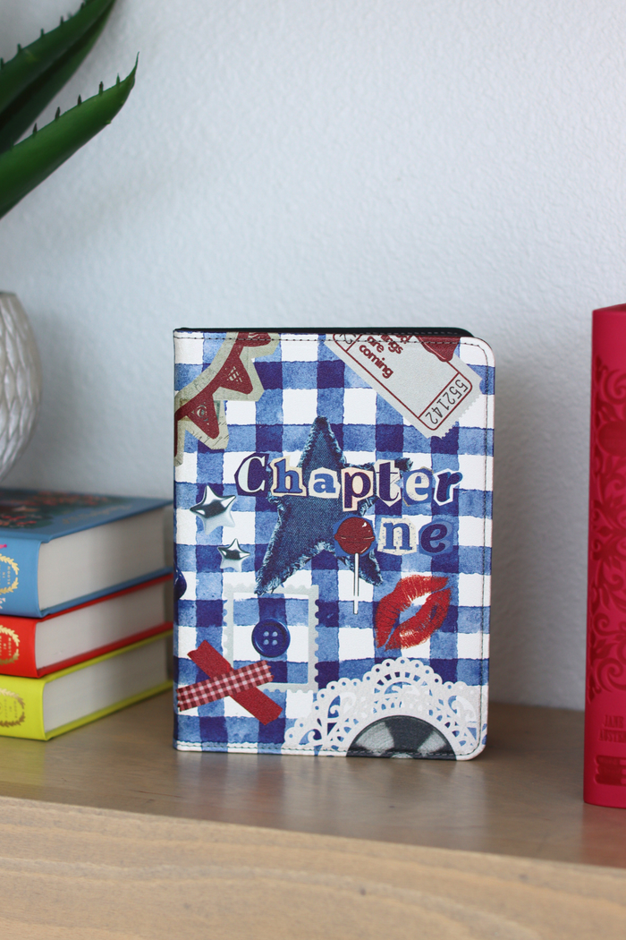 Kindle with a blue and white checkered cover on a shelf with books