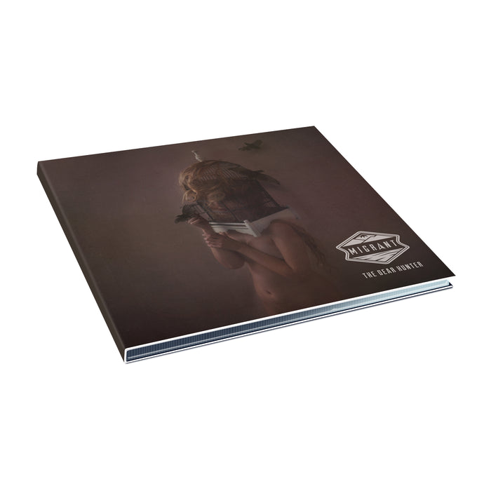 A CD case with a naked woman standing in the middle of the image. She is in room with a brown wall. She has a bird cage on her head. There are birds swirling around her. The words "Migrant" "The Dear Hunter" are in the bottom right corner.