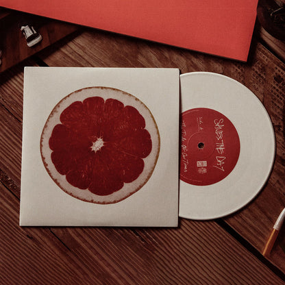 White Vinyl jacket with an image of the interior of a grapefruit. Peeking out of the sleeve is a white vinyl disc with "SAVES THE DAY" written in the center. Both are on top of a walnut colored  wooden surface.
