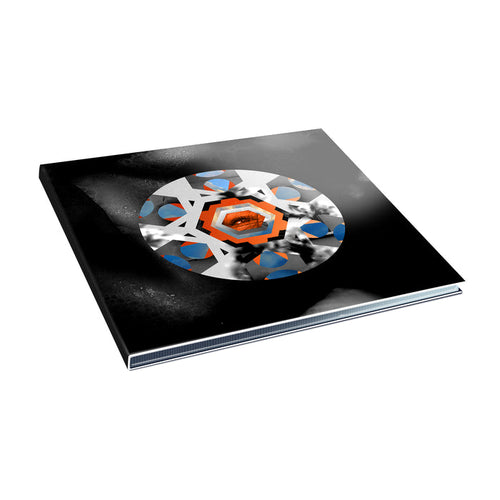 A closed book titled "The Outer Ring" by Armor For Sleep features a black cover with orange, blue, and white hexagon and circle designs. The book is shown at a slight angle against a white background.