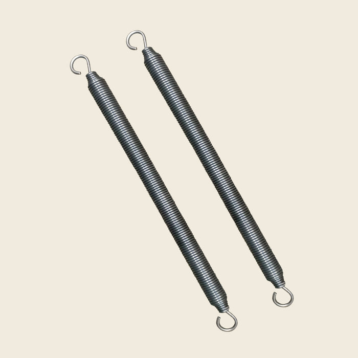 Pair of Gratz Pilates trapeze bar springs with open hook ends on beige.