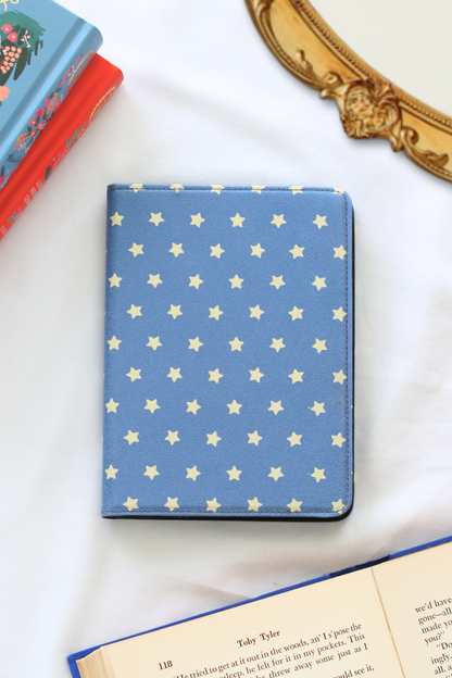 Blue Kindle Case with star pattern on a white surface with books in the background