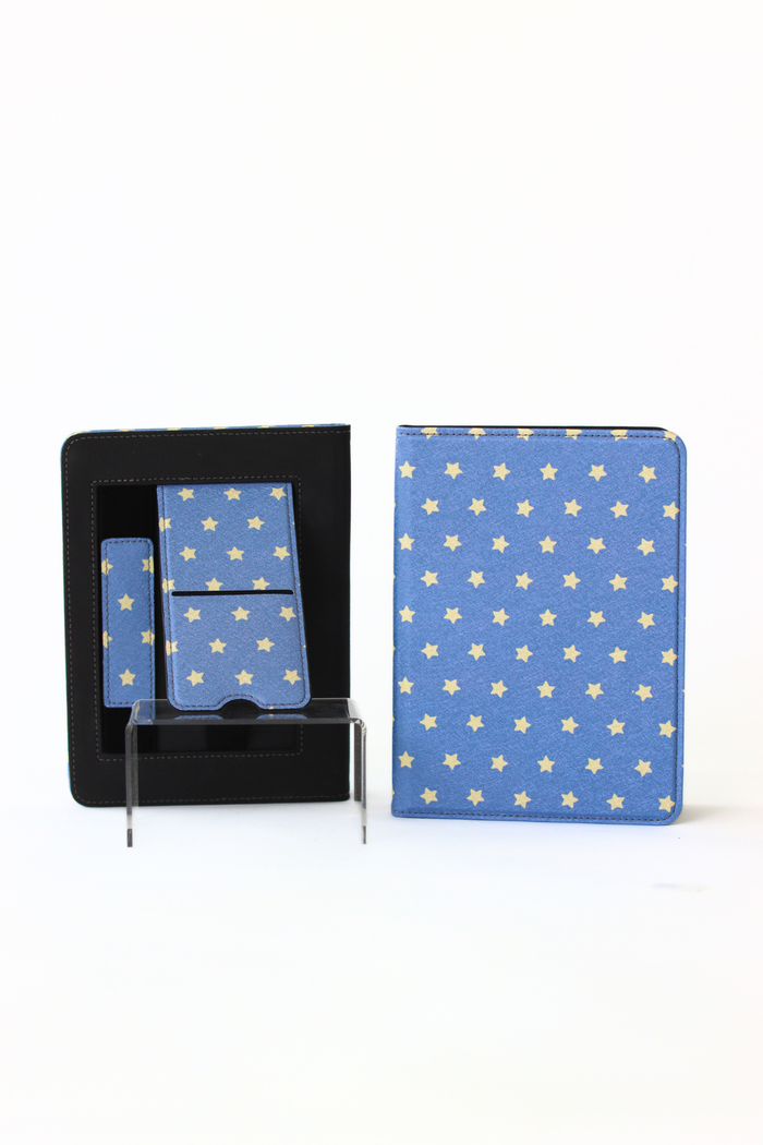 A blue stationery set with a repeating gold star pattern, shown both inside its black presentation box and standing upright on a clear acrylic display stand against a white background.