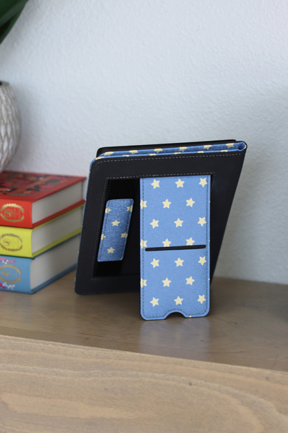 Blue Kindle Case with star pattern on a wood surface with books in the background