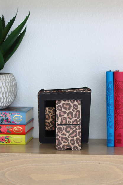 Leopard print case on a shelf with colorful books and a plant in the background