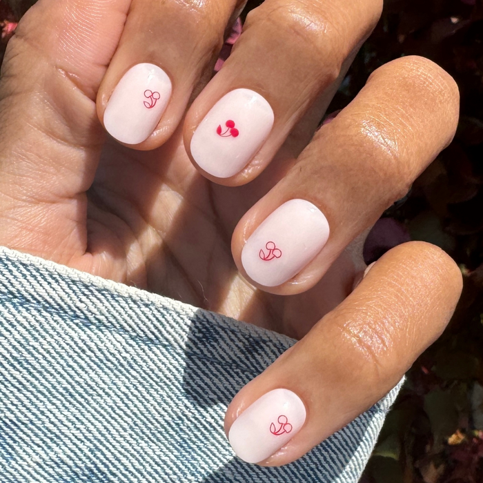 Vampy Cherry | Extra Short | Round - Tab Press-On nails in soft pink with delicate red cherry line art on natural hand outdoors